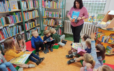 Bibliotekarka prezentuje dzieciom książkę.