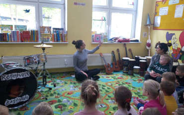 Bibliotekarka czyta dzieciom księżeczkę, dzieci siedzą w kole