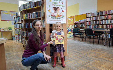 Dziewczynka wraz z bibliotekarką pokazuje nowo nabyty pakiet z akcji 