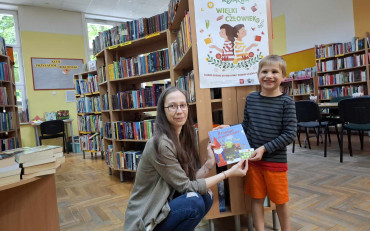 Bibliotekarka wręcza chłopcu pakiet z akcji 