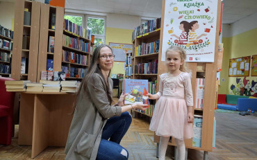 Bibliotekarka wręcza dziewczynce pakiet z akcji 