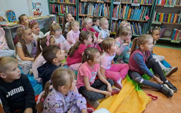 Dzieci słuchające bibliotekarkę czytającą książkę