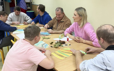 Uczestnicy spotkania siedzą przy stolikach i rysują