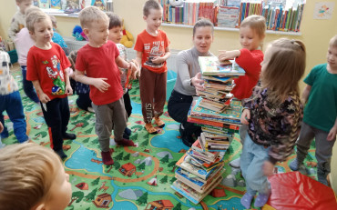 Dzieci z bibliotekarką budują wieżę z książek