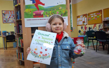 Dziewczynka pokazuje dyplom po ukończeniu zbierania naklejek z  akcji 