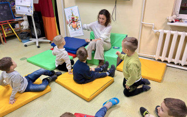 Dzieci słuchają książeczki czytanej prze bibliotekarkę