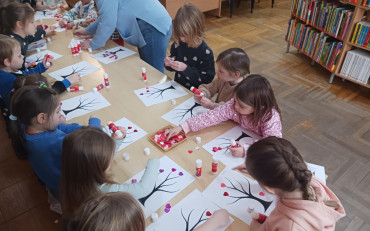 Dzieci wykonują drzewka miłosne stojąc przy stole